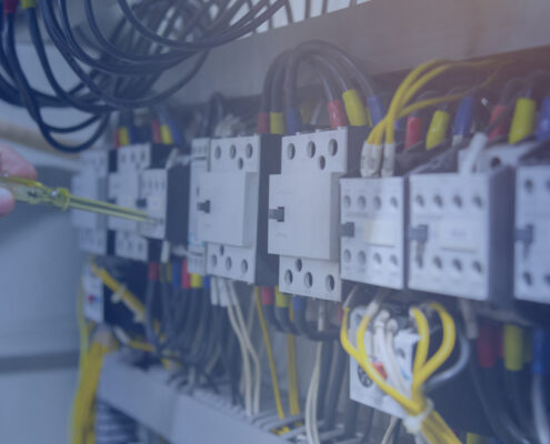 Electricians hands testing current electric in control panel blue overlay